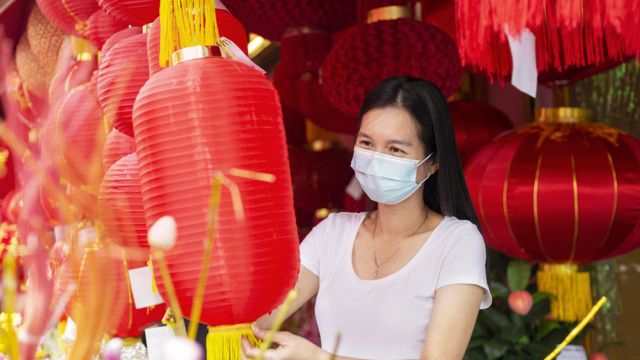 一名女子在市场上挑选传统的红灯笼，为在农历新年期间装饰自己的家做准备 ...
