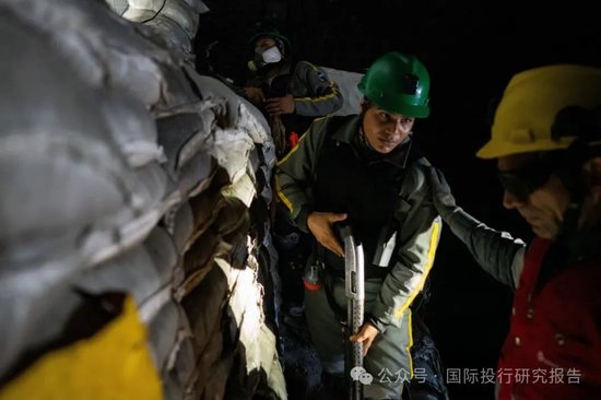 紫金矿业保安负责人在阻止非法矿工进入的障碍物前与公司武装警卫交谈